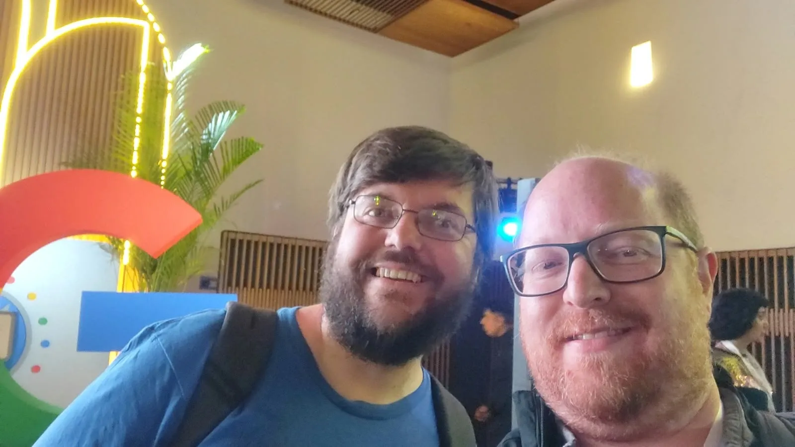Selfie de Gabriel con otro asistente en Google Search Live 2025, con el logo de Google atrás